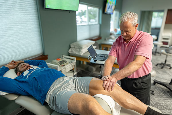 physical therapist works with patient knee