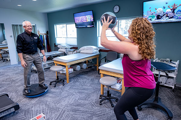 physical therapist using a medicine ball with patient